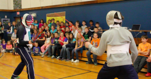 Tim Morehouse and Jeff Spear duel in front of students in Maine during their Fencing In The Schools assembly. Courtesy of Holly Buechel 